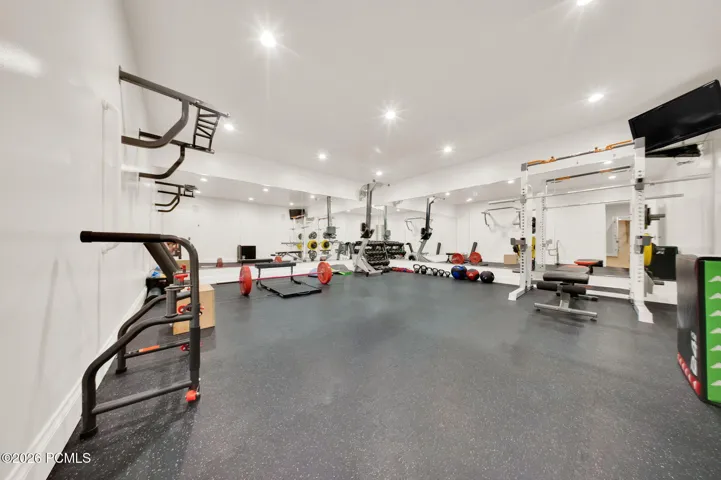 Dedicated fitness space with recessed lighting, full-wall mirrors, and resilient rubber flooring
