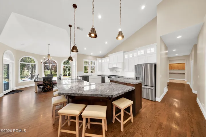 Spacious kitchen featuring a large island with seating, stainless steel appliances, white cabinetry, and recessed lighting