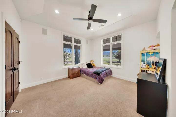 Spacious room featuring broadloom carpeting, two large windows with views of the landscape, a ceiling fan, and recessed lighting