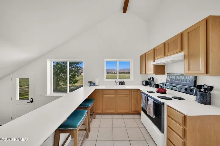 Kitchen featuring natural wood cabinetry, white countertops, a built-in electric range, and tile flooring