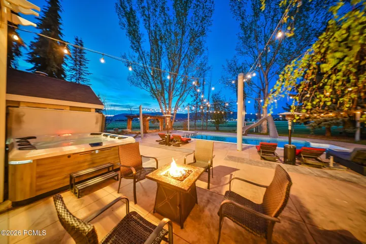 Expansive patio featuring a built-in hot tub, in-ground swimming pool, and string lighting