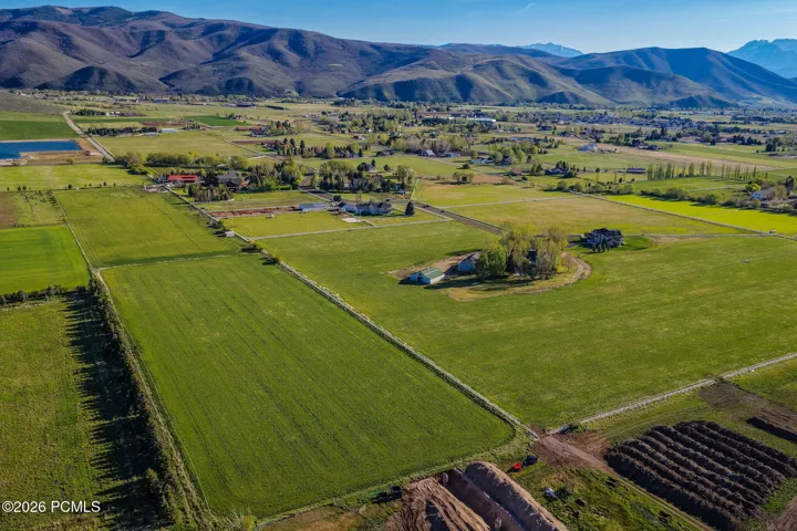 Expansive green fields featuring multiple residential structures and distant mountain ranges