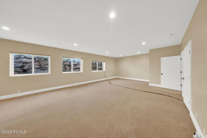 Spacious room featuring neutral wall paint, recessed lighting, white baseboards, and light brown carpet flooring