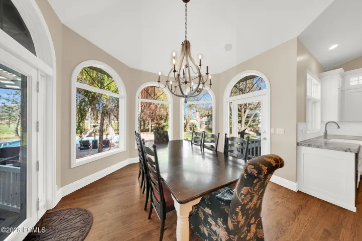 Dining area with vaulted ceilings, hardwood flooring, and multiple arched windows