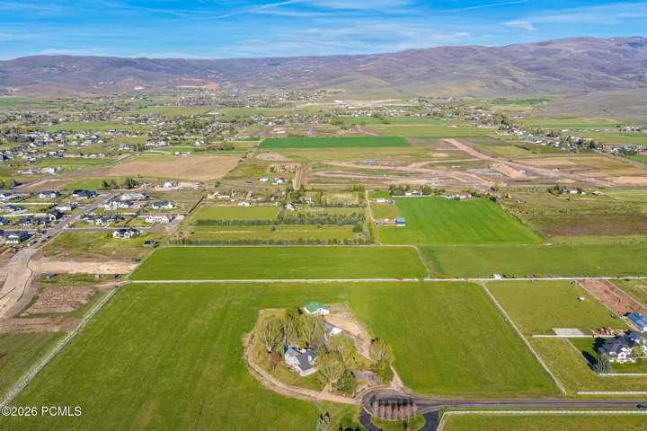 Expansive agricultural land featuring a single-family residence, mature trees, and mountainous terrain