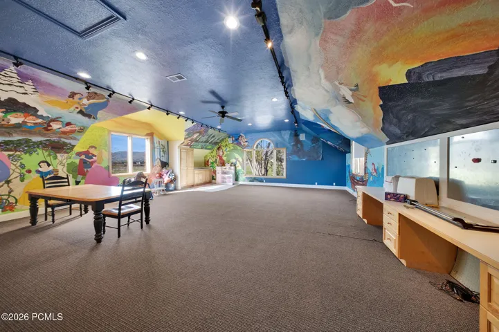 Spacious room or bedroom featuring murals, track lighting, built-in cabinetry, a window, and carpet flooring