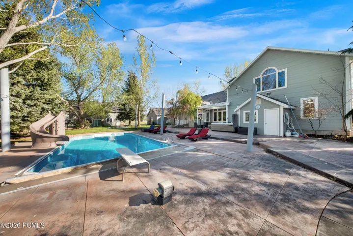Expansive backyard featuring a rectangular swimming pool with an integrated slide and diving board