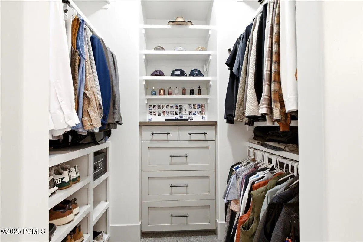 Walk-in closet featuring built-in cabinetry with shaker-style drawers and a wood-finish countertop