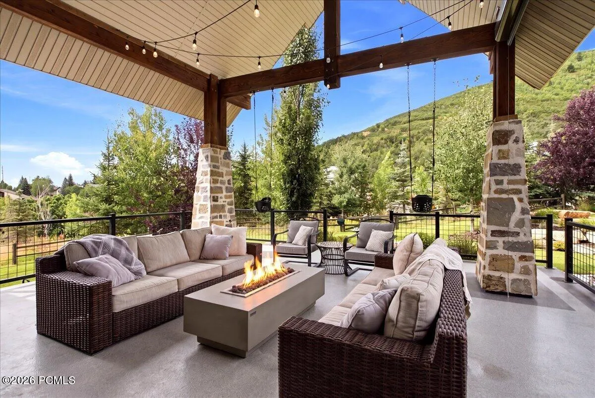 Expansive covered patio featuring a built-in fire pit, stone-clad columns, and wood beams
