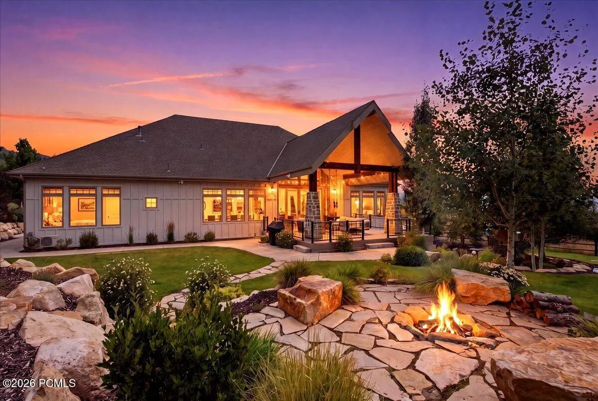 Expansive outdoor living area featuring a flagstone patio with a built-in fire pit, surrounded by natural rock landscaping