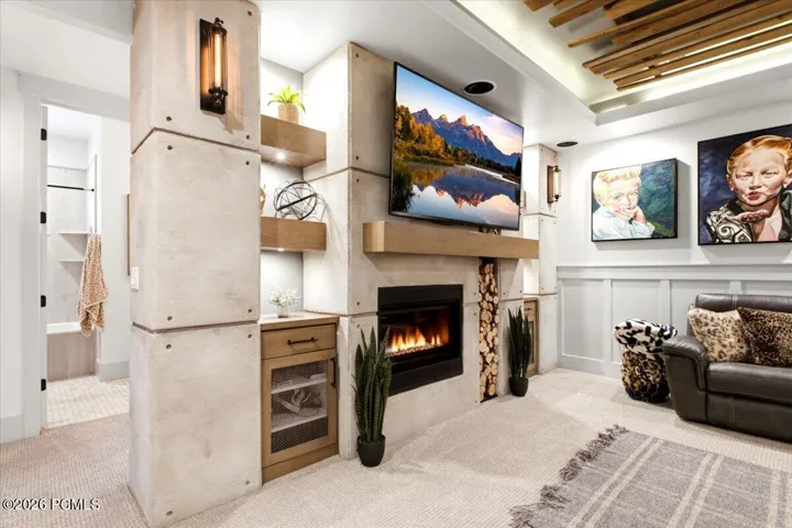 Integrated media wall featuring a built-in fireplace with a stone surround, floating wood mantel, and wood-finish shelving