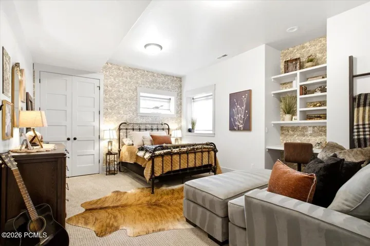 Bedroom featuring a decorative accent wall, built-in shelving, two windows, and paneled bifold doors