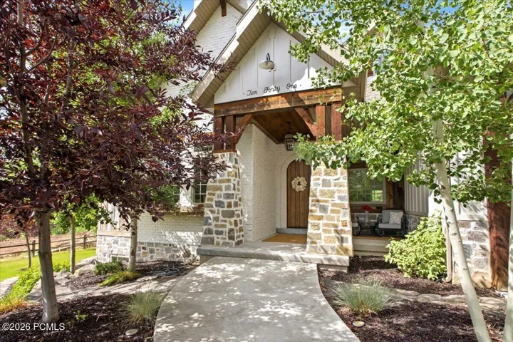 Front entry featuring stone, brick, wood-beams, and a solid wood arched door