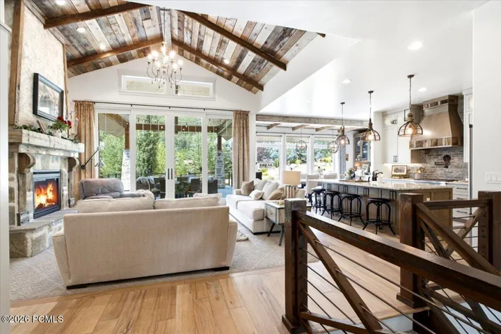 Open-concept living area with vaulted wood-plank ceilings, a stone fireplace, and large sliding glass doors