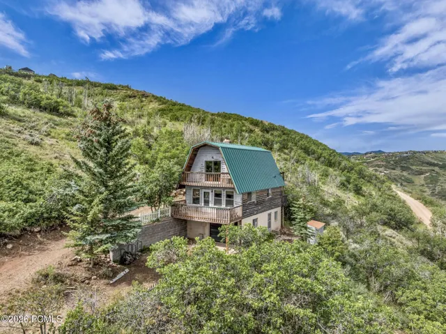 A green metal gable roof, nestled on the hill top.