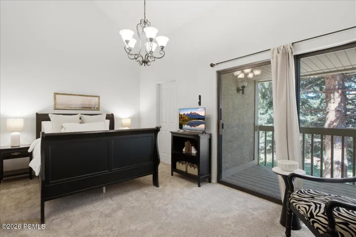 Vaulted ceilings elevate this primary suite, with direct access to a private tree-lined balcony.