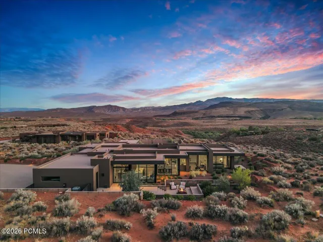 Modern desert architecture featuring extensive fenestration, a private patio, and a built-in fire pit