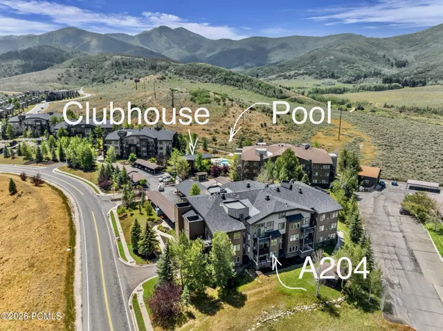 Aerial perspective showcasing, community pool, clubhouse, and location of condo. Set against a mountainous backdrop.