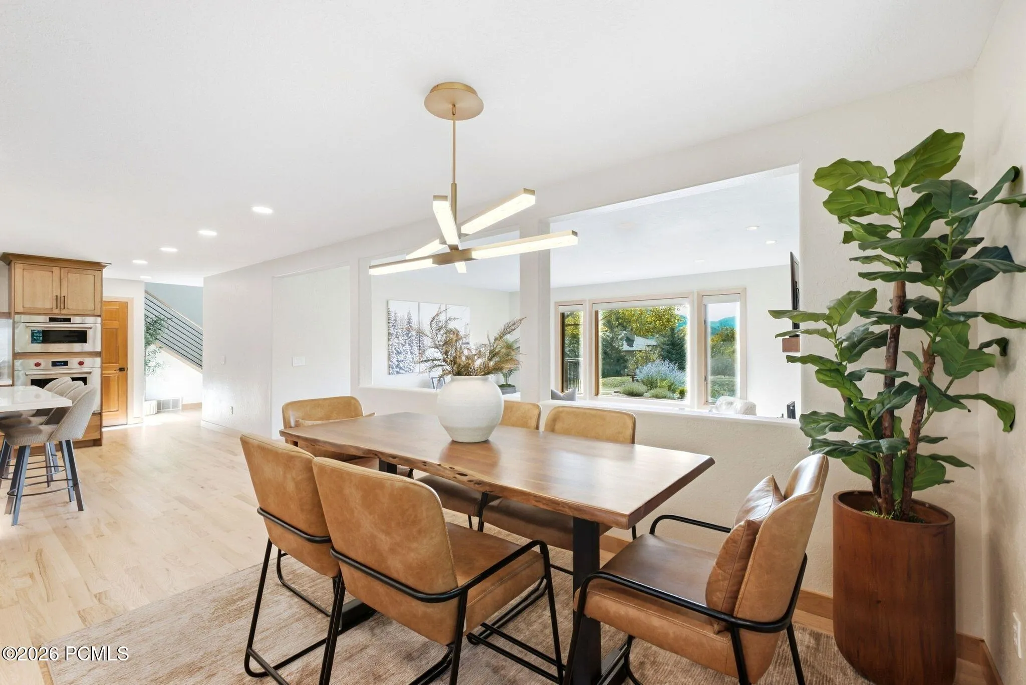 Open concept kitchen, dining, and living area. Refinished wood flooring throughout, updated lighting, wood-framed windows with wooden shutters, natural light and views.
