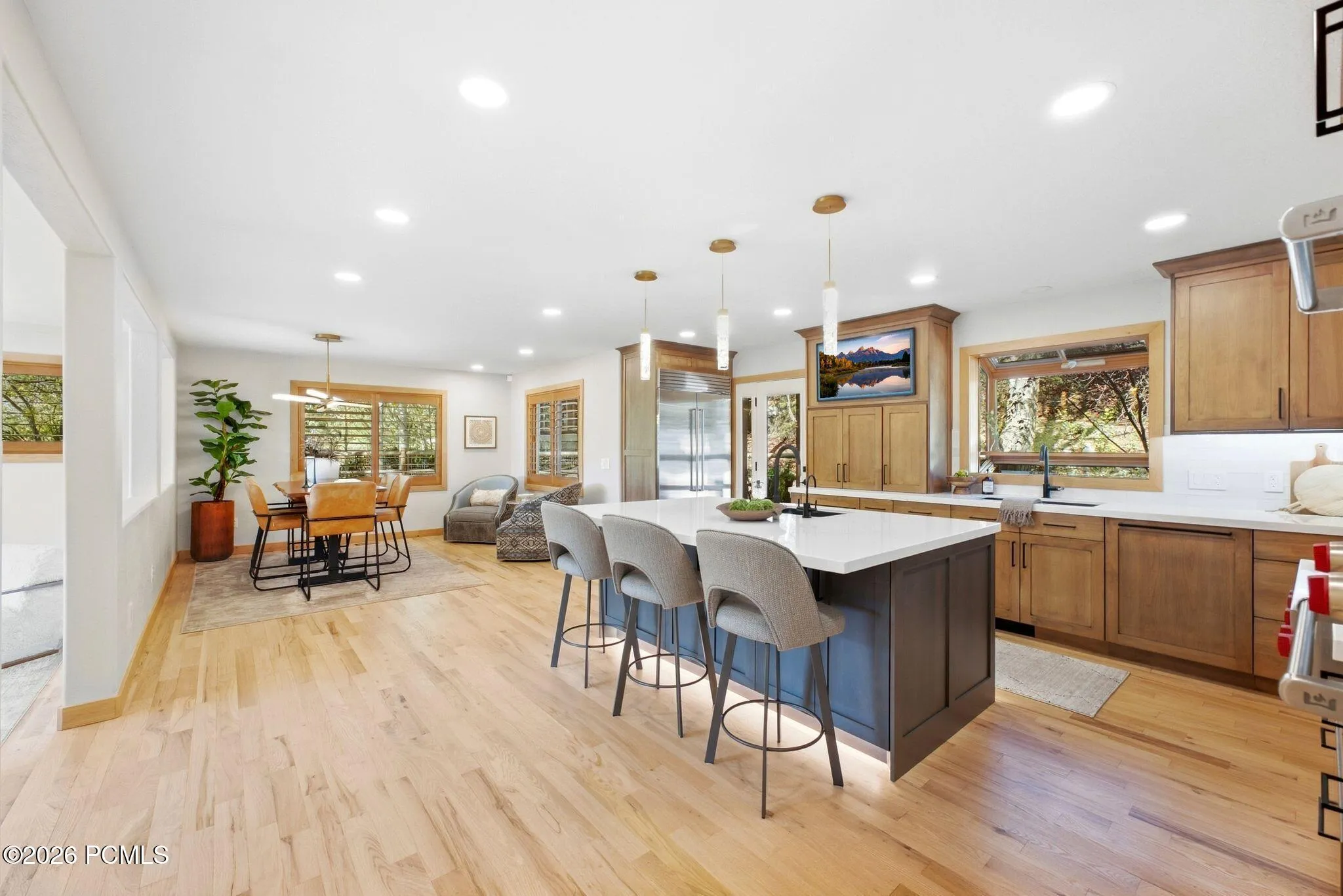 Kitchen featuring a center island with under-cabinet lighting, stainless steel double Wolf ovens (convection and steam), high-end wood-finish cabinetry, and light refinished wood flooring