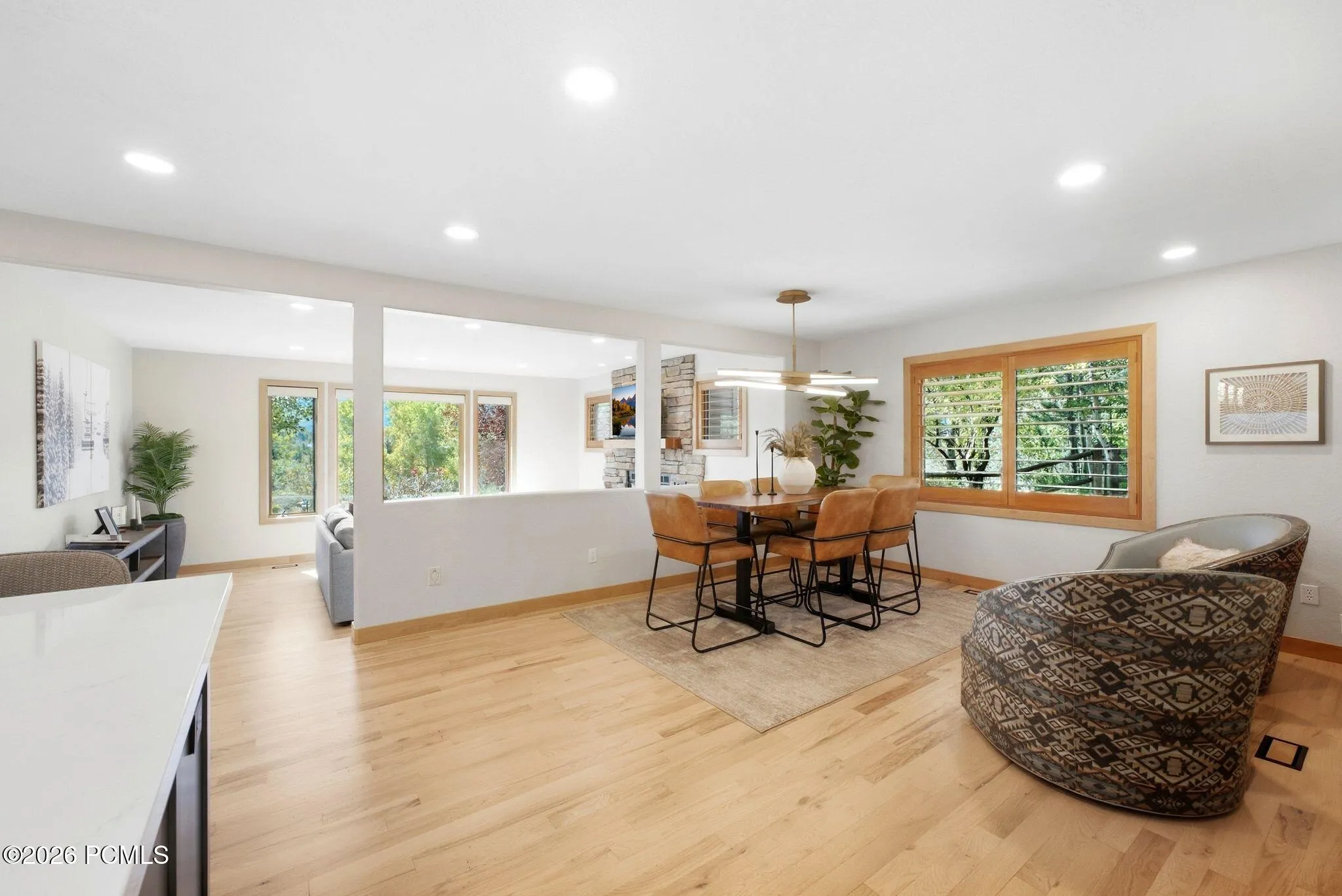 Open concept kitchen, dining, and living area. Refinished wood flooring throughout, updated lighting, wood-framed windows with wooden shutters, natural light and views.