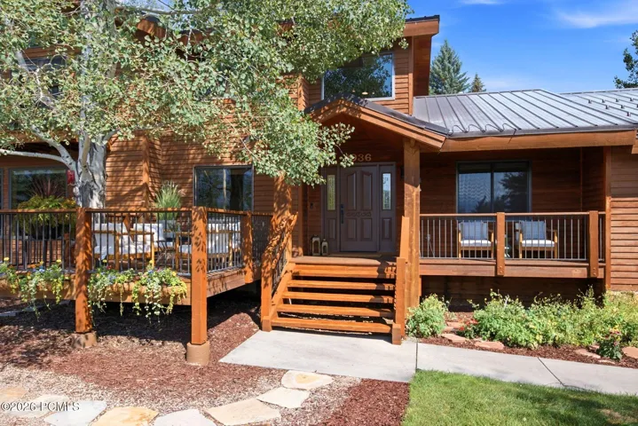 Front exterior entrance view featuring a seating area and a large front deck built around a tree so you can enjoy the views and be one with nature.