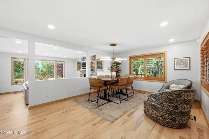 Open concept kitchen, dining, and living area. Refinished wood flooring throughout, updated lighting, wood-framed windows with wooden shutters, natural light and views.