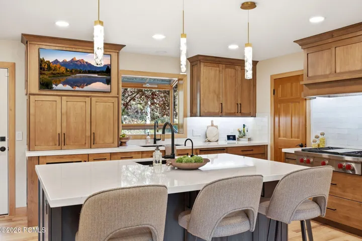 Updated kitchen (2024) featuring Ethereal Glow quartz countertops, updated lighting, high-end cabinetry, under-mount sink with a matte black faucet, and a Wolf range.
