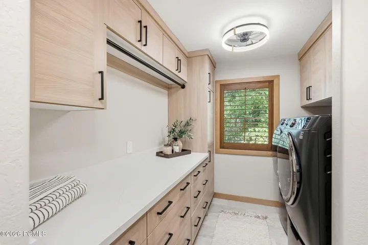 Updated laundry room with heated flooring featuring ample storage wood-Valor Gold Lava quratz countertops new washer and dryer units that stay with the home, and it even has its a built in broom closet.