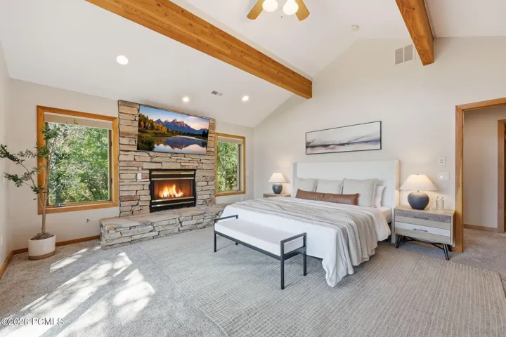 Primary bedroom with vaulted ceilings, fireplace, a private deck, incredible views of the mountains and ski resorts, an en-suite bathroom with a separate jetted tub and shower, heated floors and a walk-in closet.