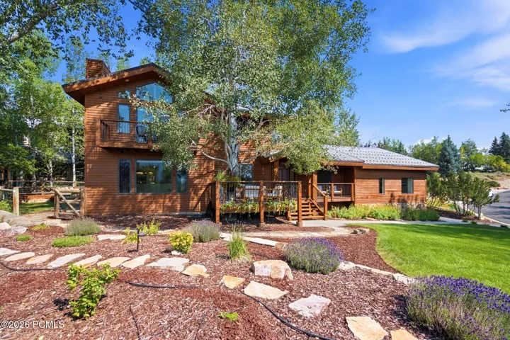 Front exterior featuring the primary bedroom balcony, front porch, entrance, grass and xeriscaping.