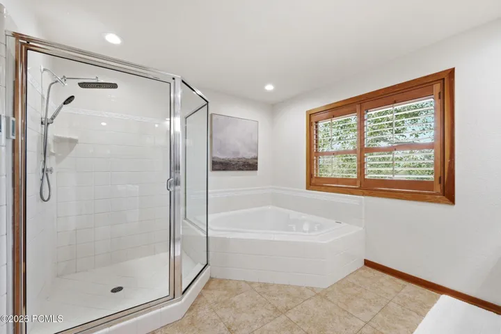 Primary bathroom boasts a jetted tub, heated floors, a stand-alone shower, a walk-in closet, an updated vanity and lighting, and double sink with Taj Mahal quartzite counters
