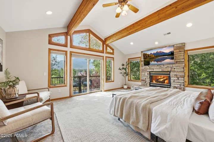Primary bedroom featuring exposed wooden beams, private balcony, fireplace, seating area, ensuite bathroom with heated floors, a jetted tub, stand alone shower, and walk-in closet. Wake up to the incredible views of the mountains.