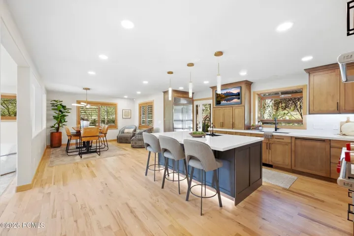 Kitchen featuring a center island with under-cabinet lighting, stainless steel double Wolf ovens (convection and steam), high-end wood-finish cabinetry, and light refinished wood flooring