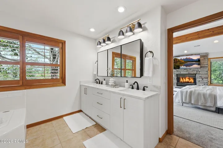 Primary bathroom boasts a jetted tub, heated floors, a stand-alone shower, a walk-in closet, an updated vanity and lighting, and double sink with Taj Mahal quartzite counters