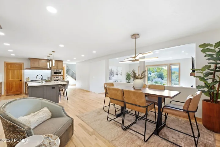 Open concept kitchen, dining, and living area. Refinished wood flooring throughout, updated lighting, wood-framed windows with wooden shutters, natural light and views.