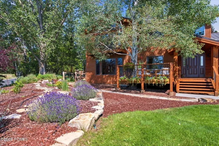 Front exterior featuring the primary bedroom balcony, front porch, entrance, grass and xeriscaping.