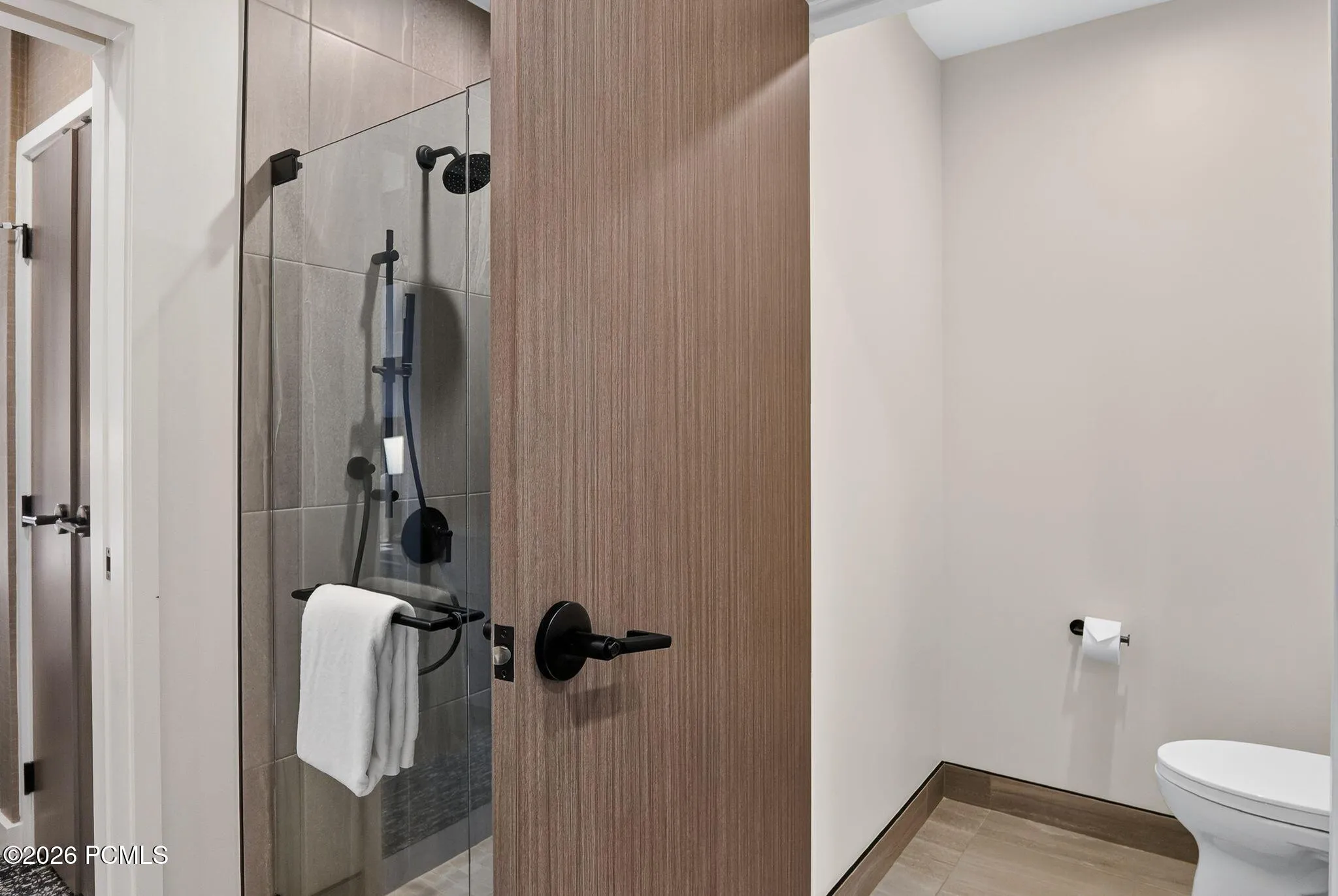 Guest bath walk in shower with wood detailing and matte black fixtures at Pendry Park City.