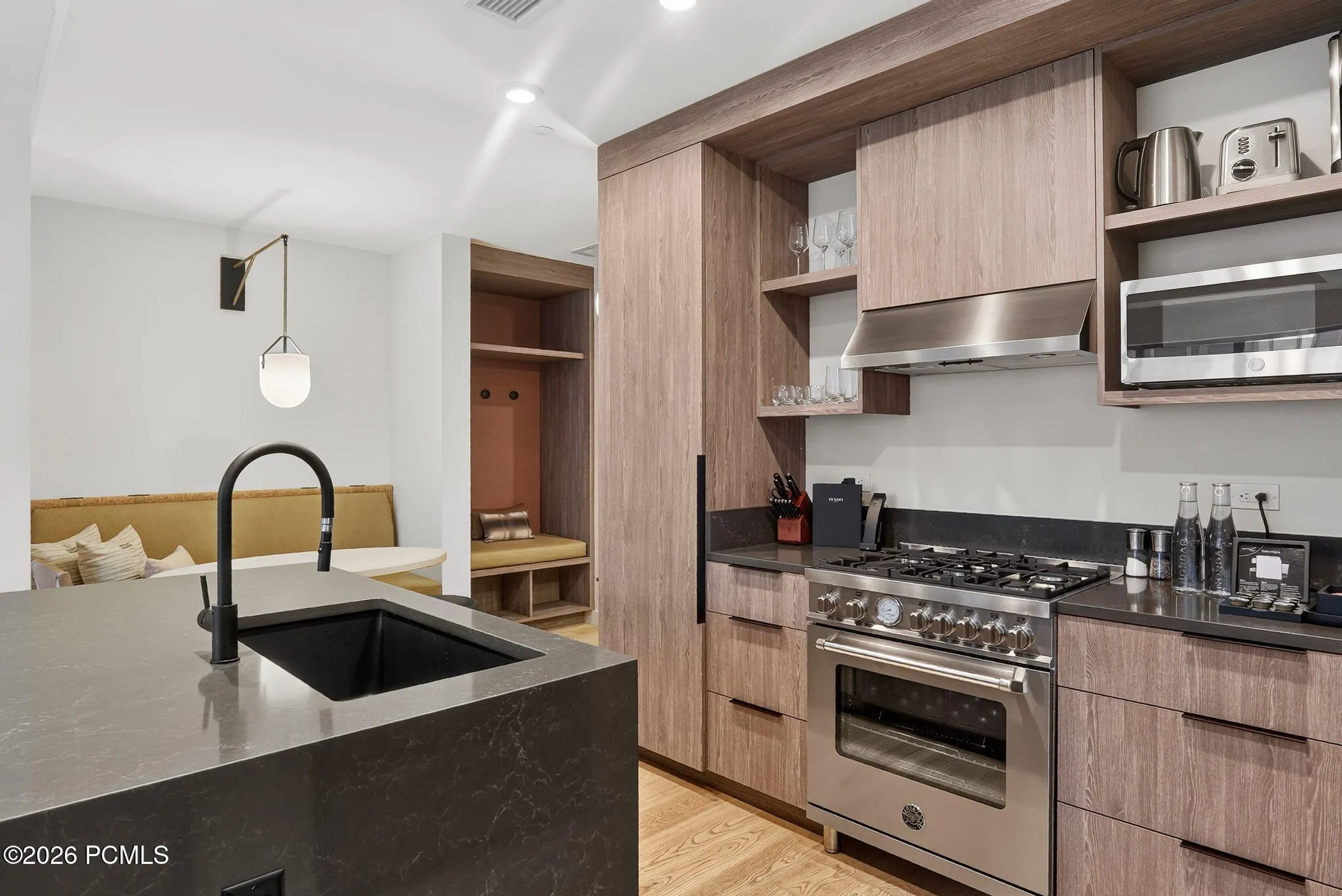Chef kitchen with a gas range, quartz island with prep sink and open shelving.