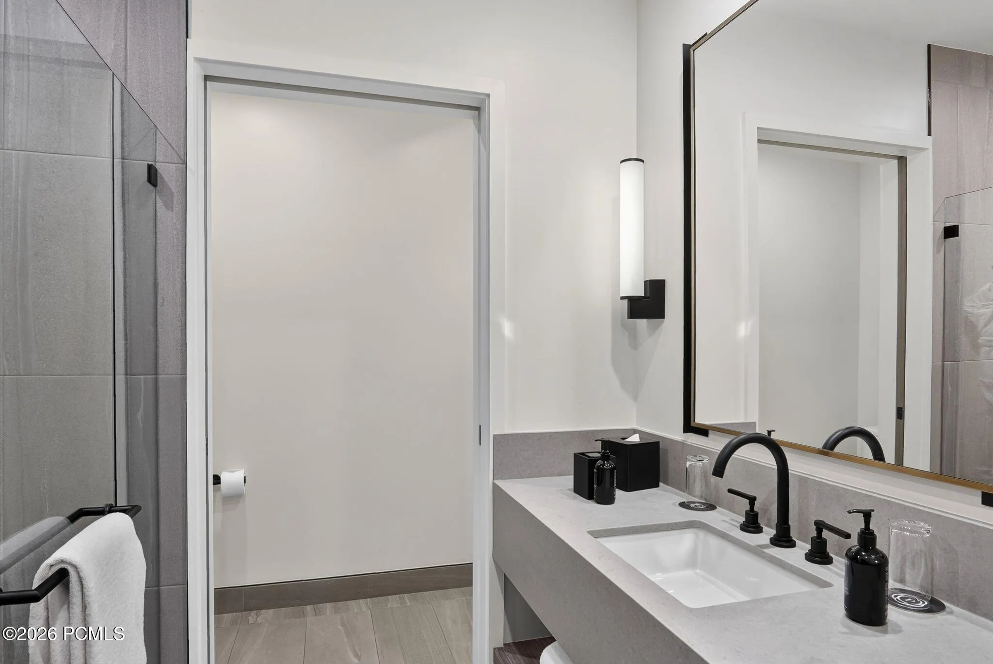 Guest bath with a double vanity, backlit mirror and glass enclosed shower.