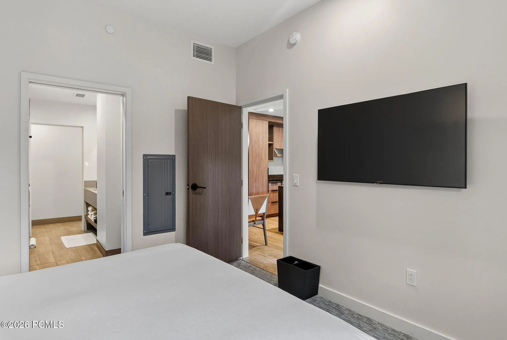 Guest bedroom with a mounted television and doorway to the ensuite bath.