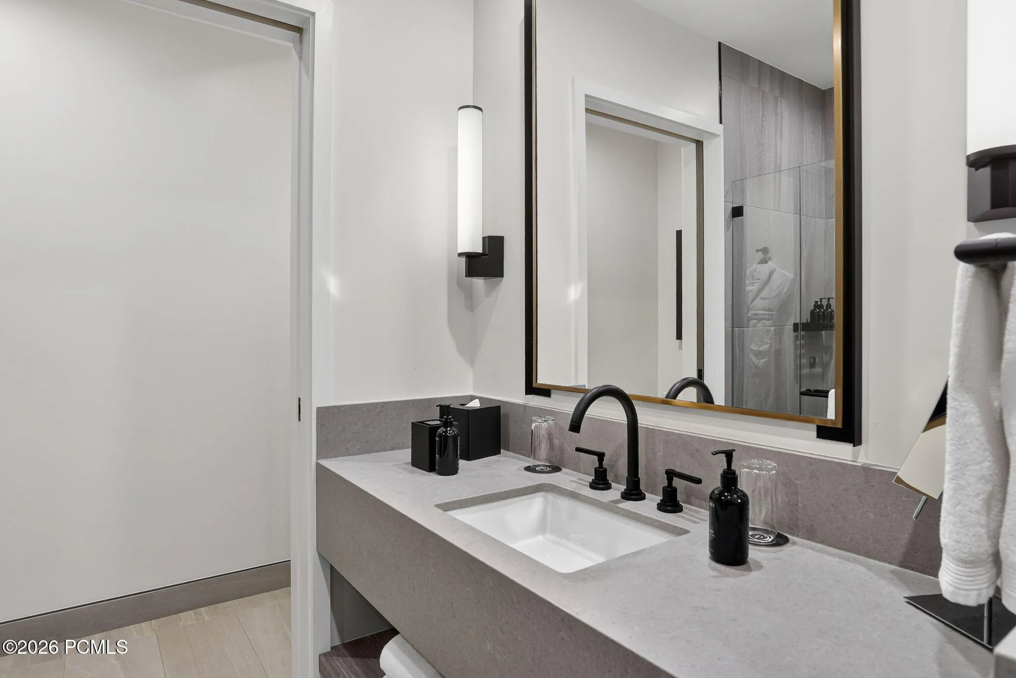 Guest bath with a quartz vanity, backlit mirror and walk in shower.