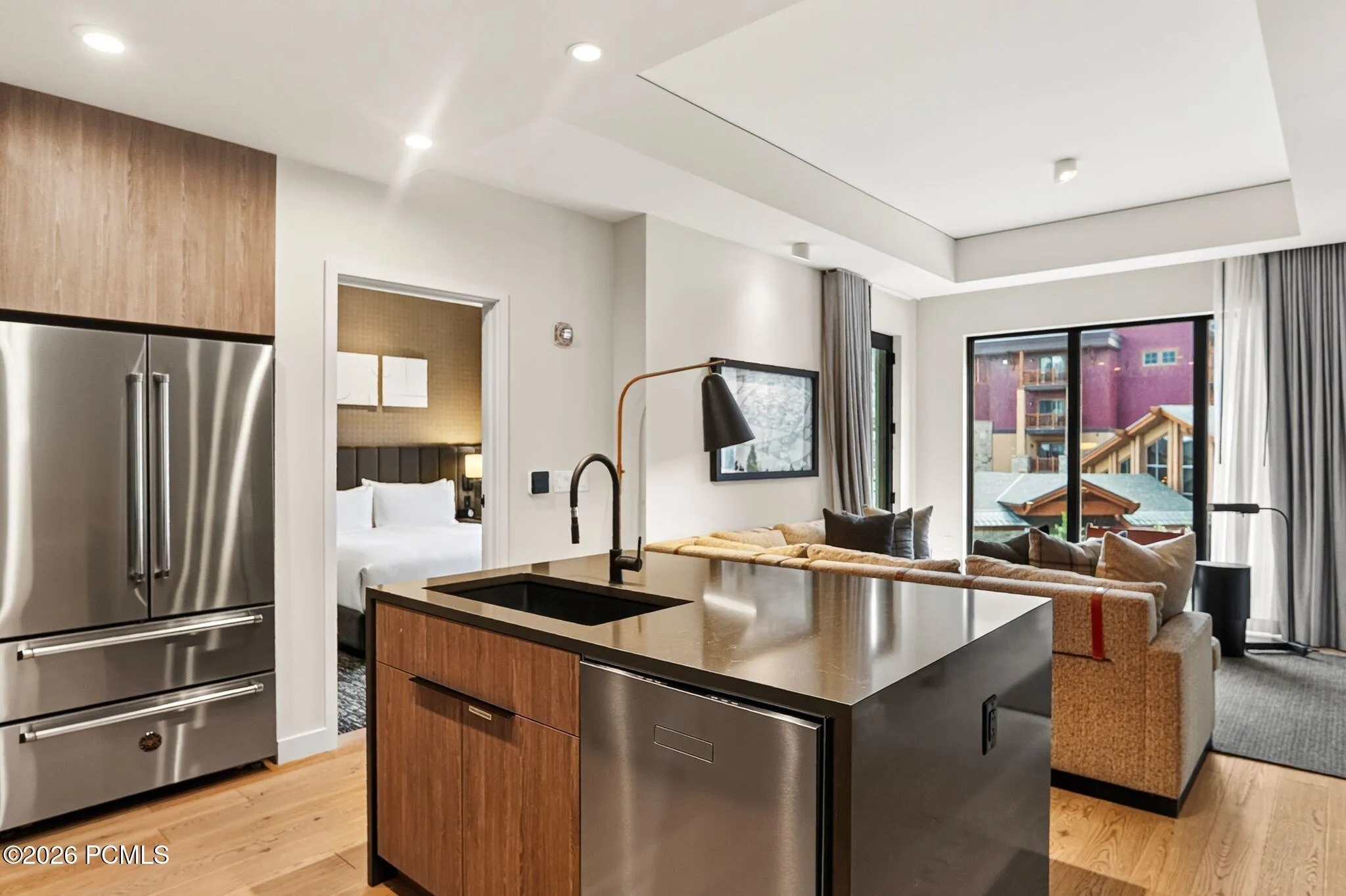 Kitchen with a stainless refrigerator and island sink, open to the living room.