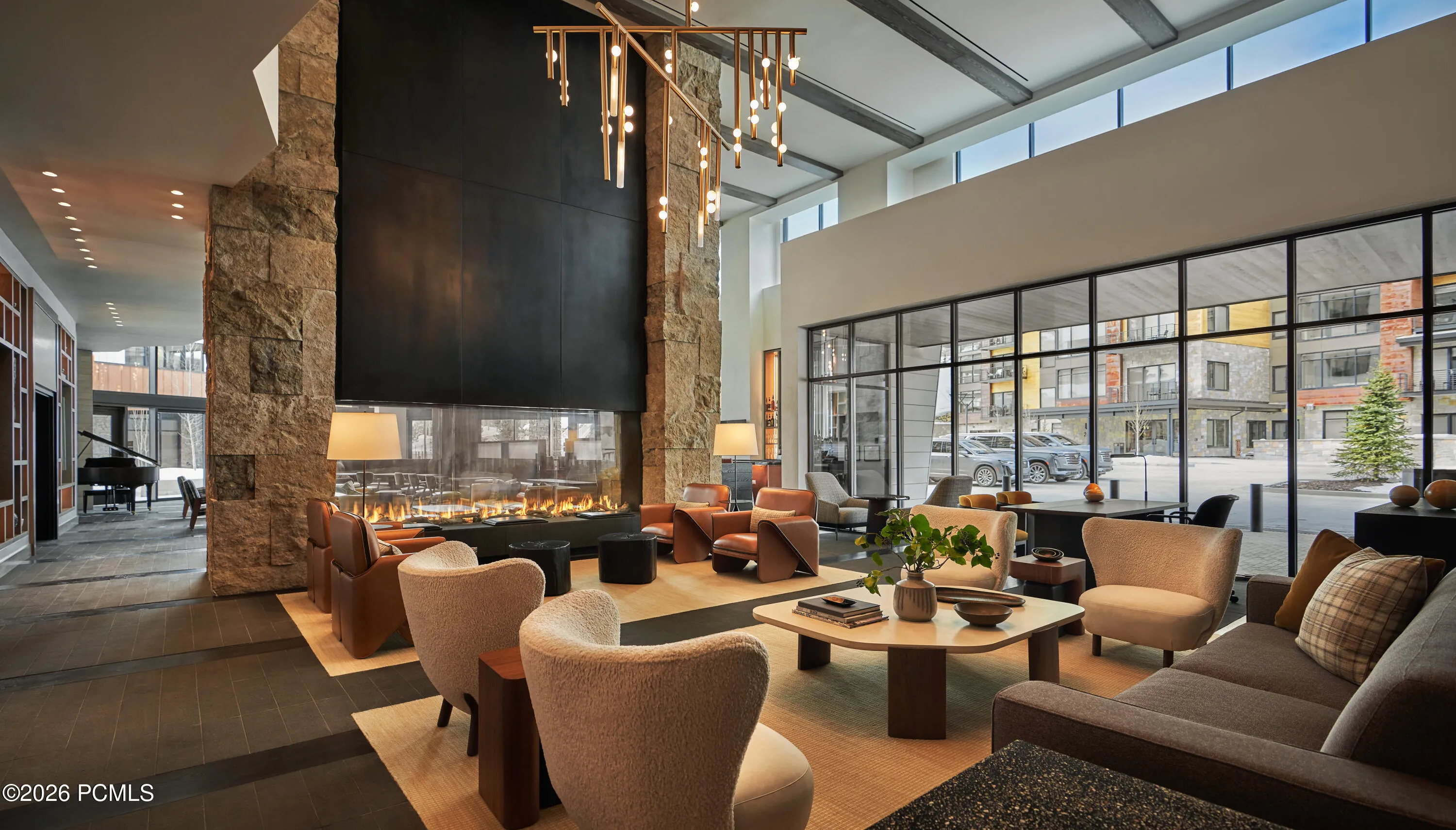 A two story stone fireplace anchors the Pendry Park City lobby great room, open to Canyons Village through floor to ceiling glass.