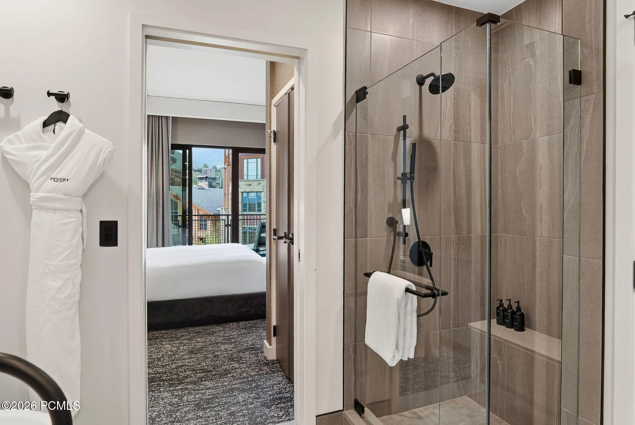 Primary bath walk in shower with bench seating and spa robes, open to the bedroom.
