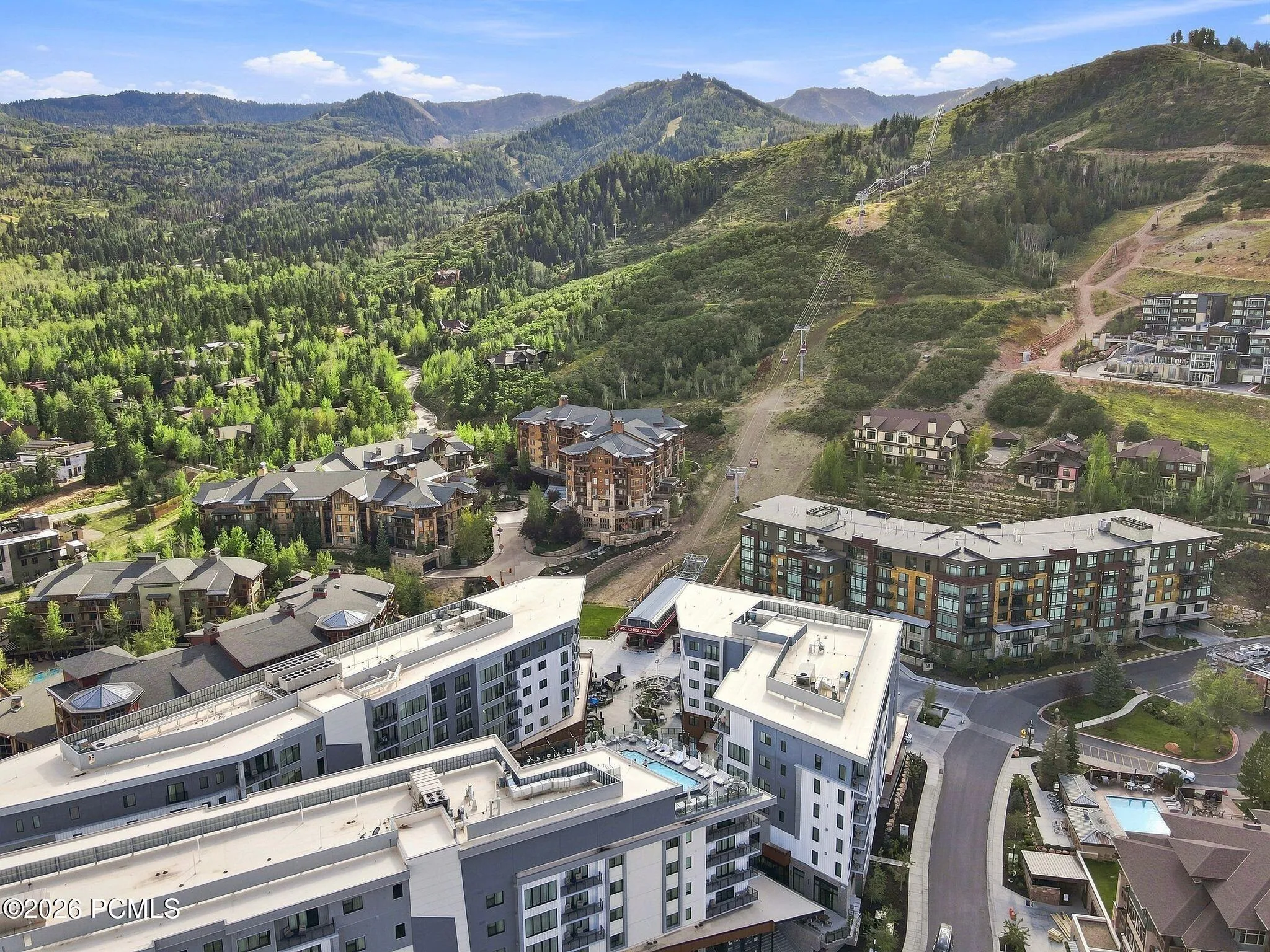 Aerial of Pendry Residences Park City with Canyons Village ski terrain rising behind the building.