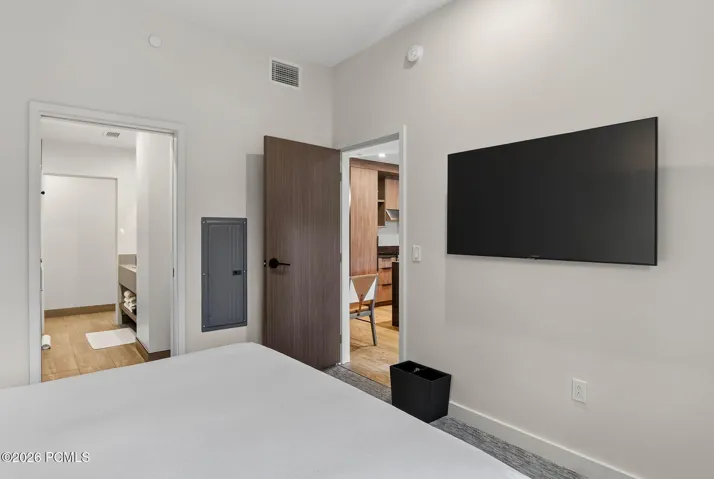 Guest bedroom with a mounted television and doorway to the ensuite bath.