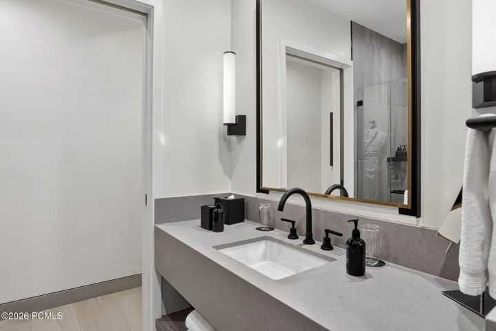 Guest bath with a quartz vanity, backlit mirror and walk in shower.