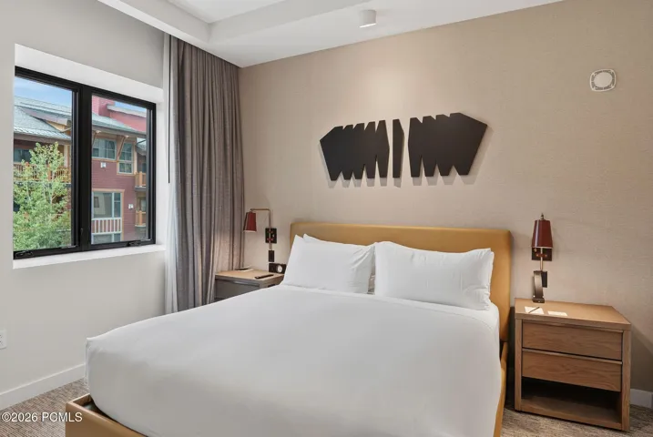 Primary bedroom king suite with custom headboard wall and mountain light at Pendry Park City.