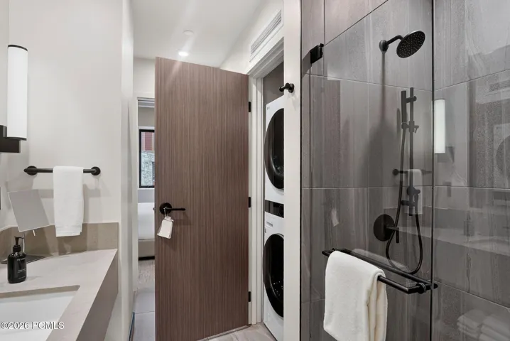 Bath with a walk in shower and full size stacked washer and dryer in the residence.